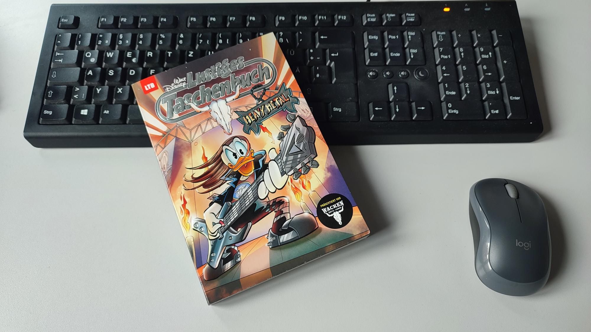 Die Metal-Ausgabe des Lustigen Taschenbuchs liegt auf einem Schreibtisch. Man sieht noch eine Tastatur und eine Computermaus.