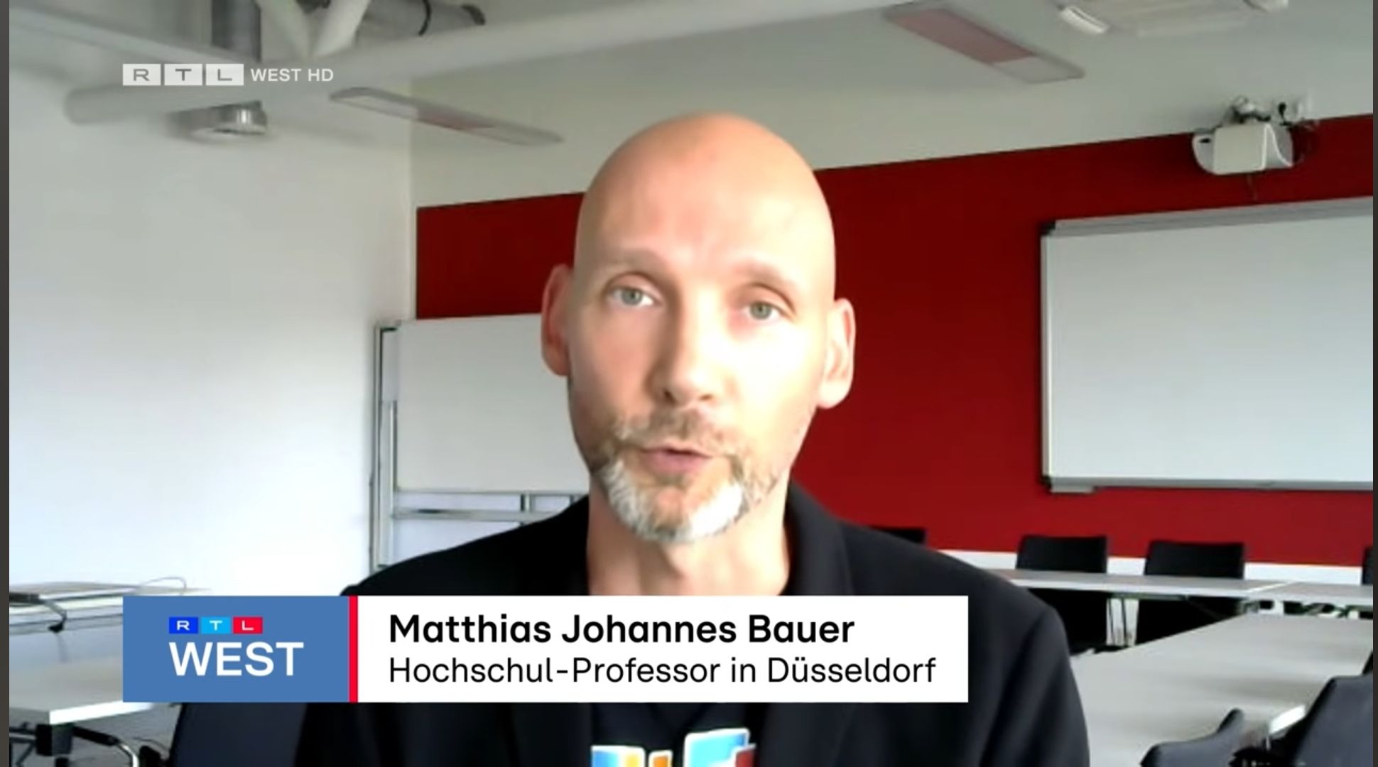 Screenshot des Videointerviews mit Festivalprof Matthias Johannes Bauer in einem Hörsaal.