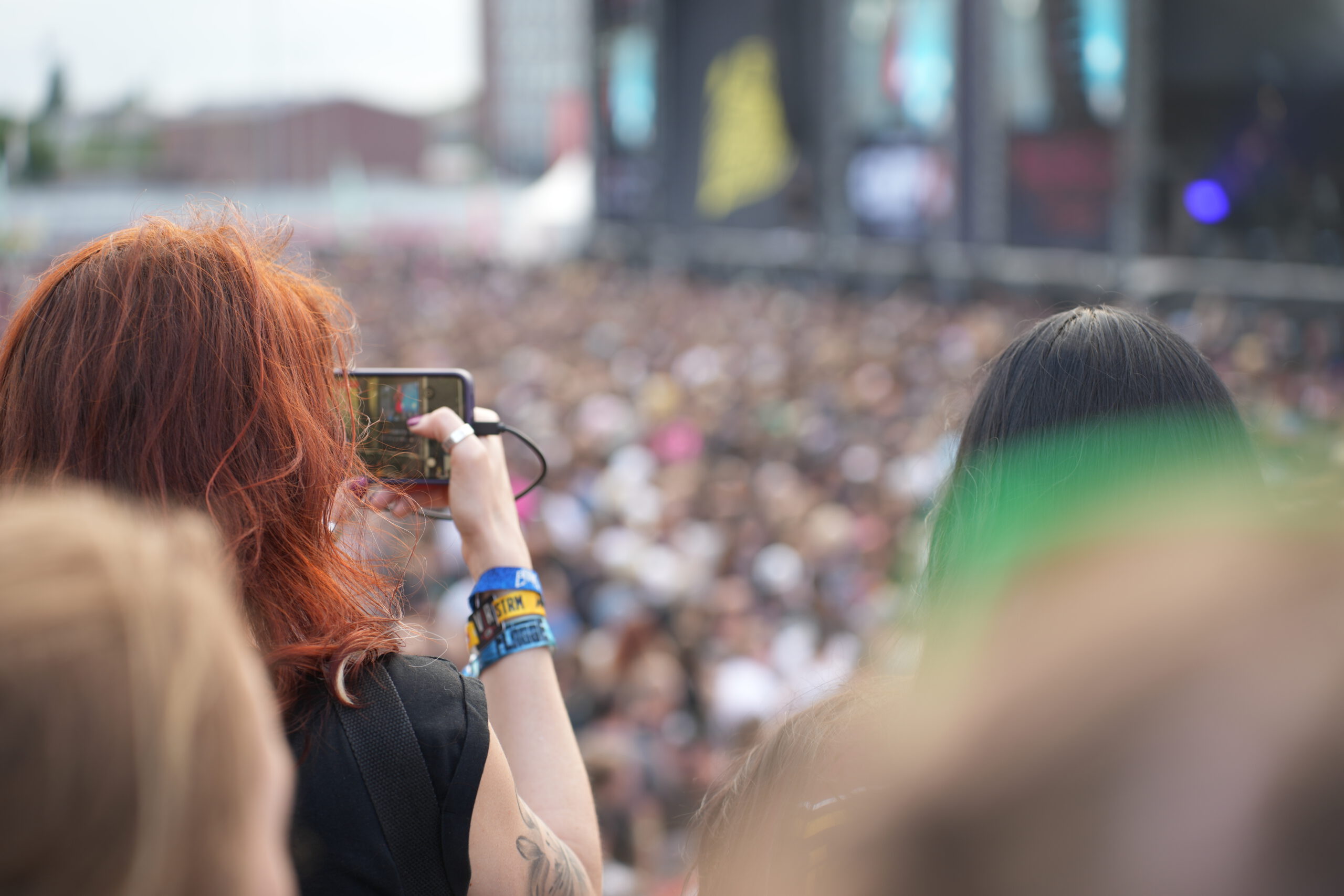 Jemand filmt eine Festivalbühne aus größerer Entfernung mit dem Smartphone.
