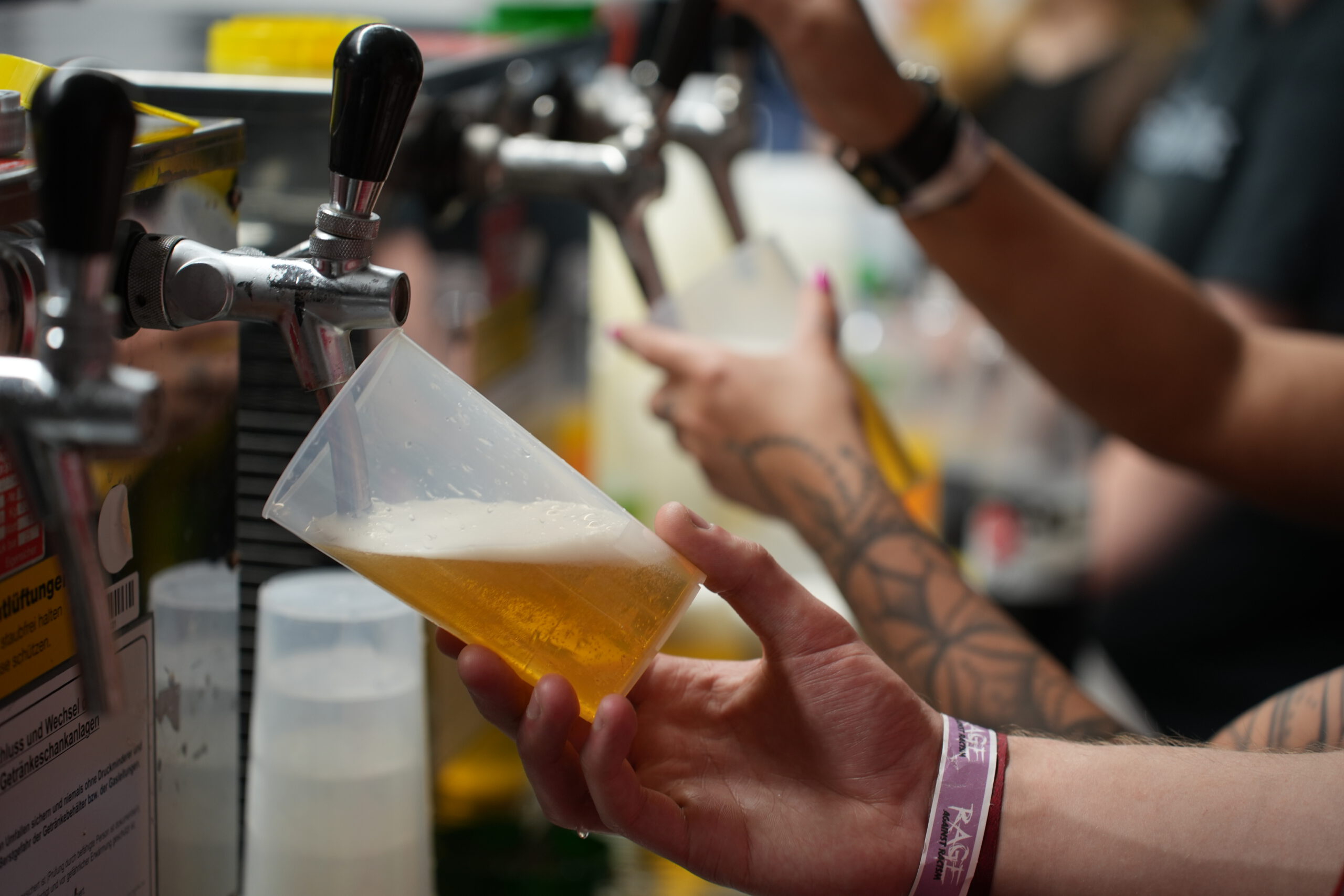 Aus Zapfhähnen fließt Bier in Festival-Mehrwegbecher.